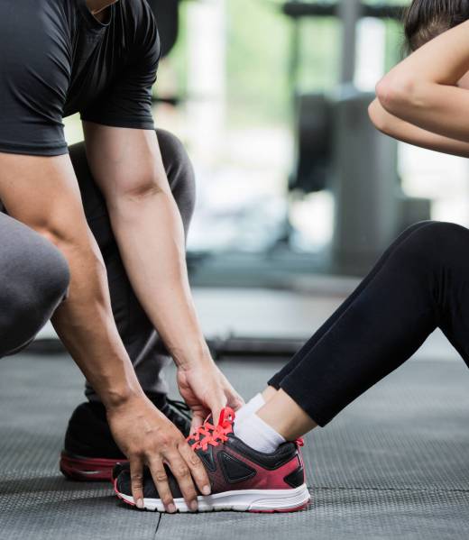 Trainer holding a woman in the leg exercise by Sid-ups.